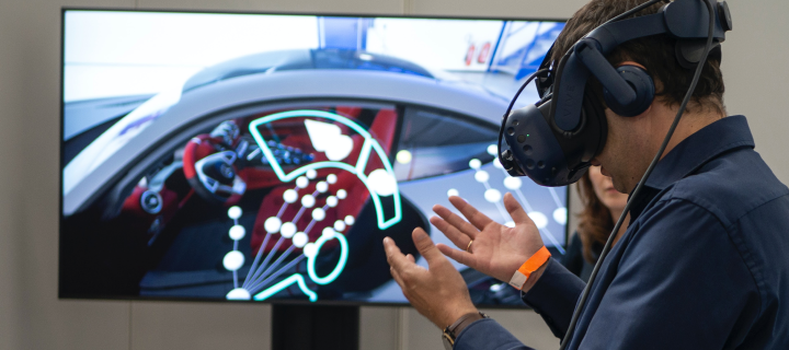 A man at a tech conference wears a headset and looks at his hands